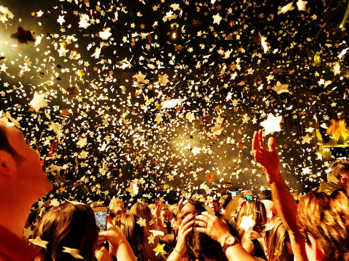 A crowd celebrating under falling gold confetti